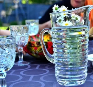 A pitcher of water beside a glass of wine elegantly placed on a wooden table.